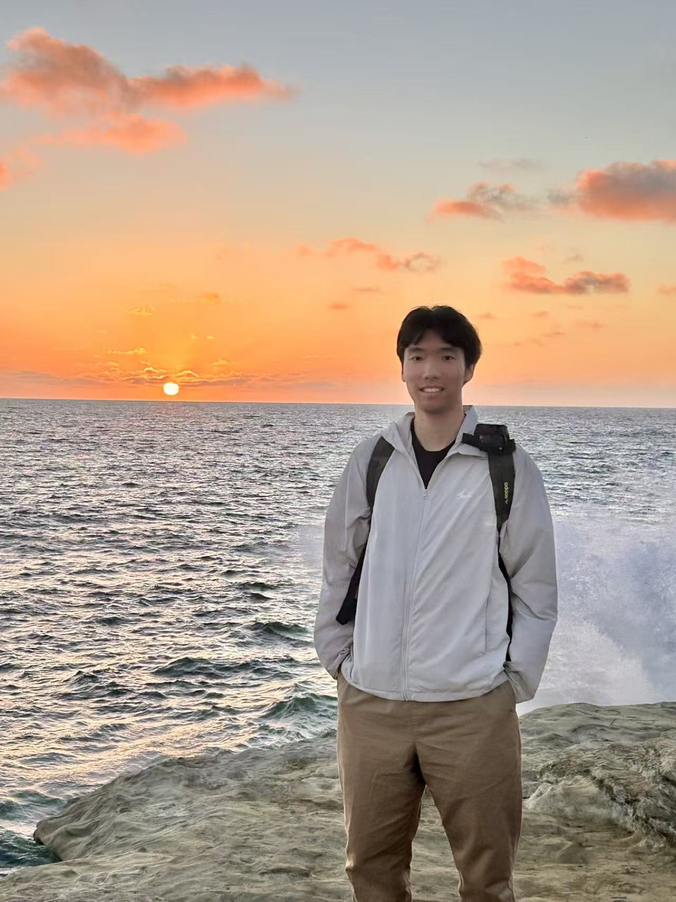Hao Yu standing by the ocean at sunset